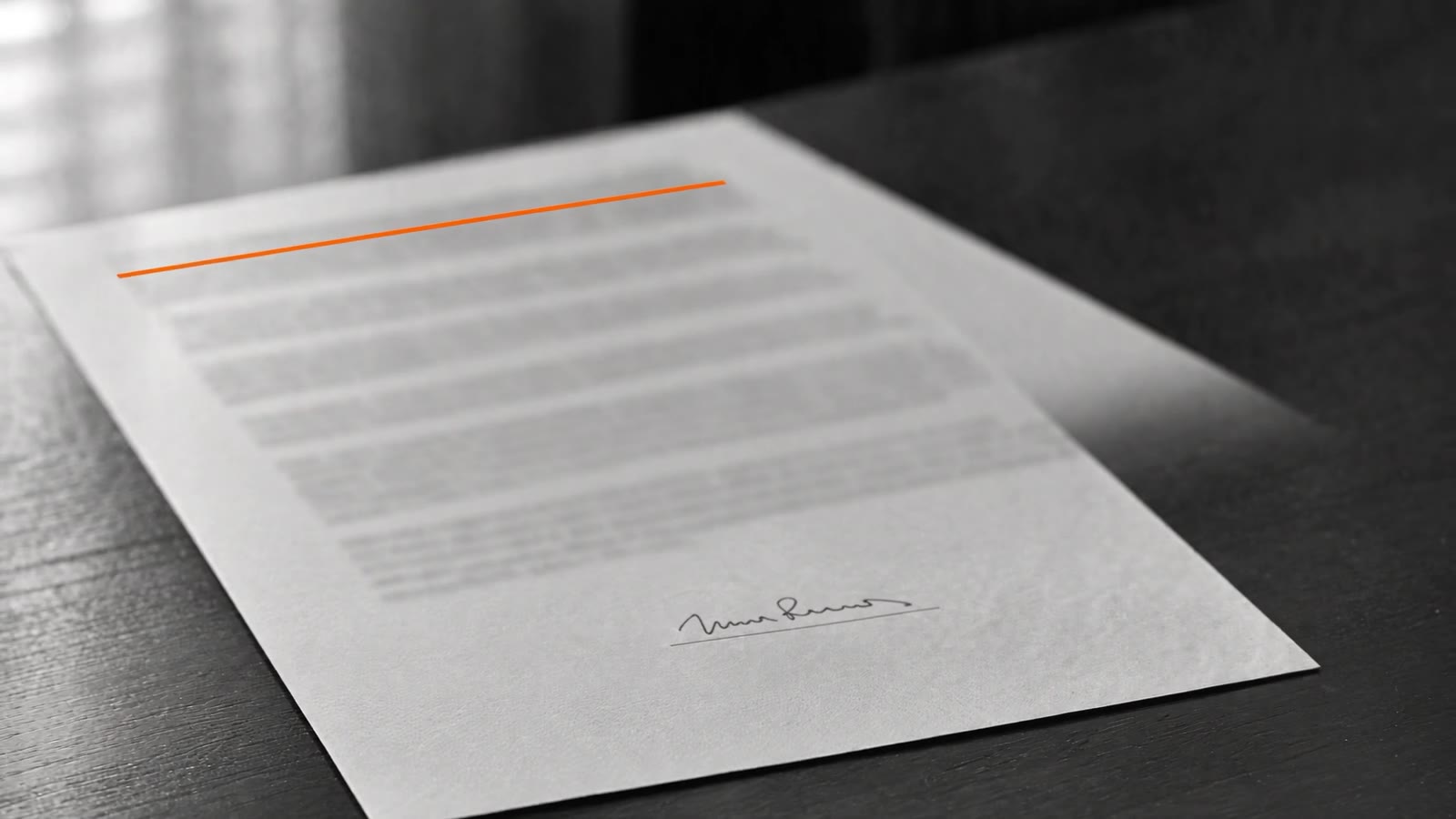 Contrato assinado sobre uma mesa de escritório, com uma linha laranja no cabeçalho.